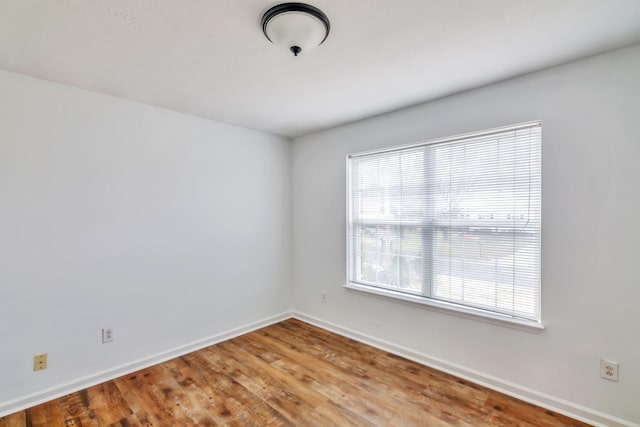 spare room featuring baseboards and wood finished floors