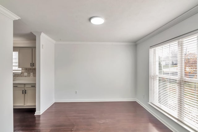 spare room with dark wood-style floors, crown molding, and baseboards