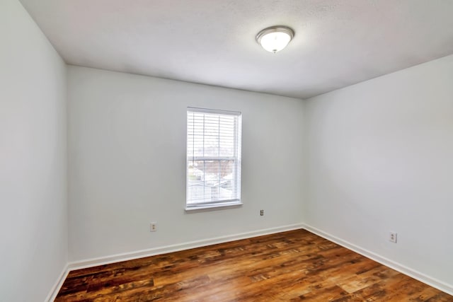 unfurnished room featuring dark wood-style floors and baseboards