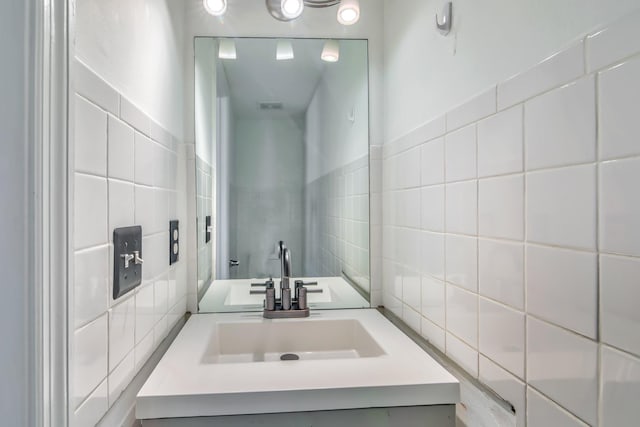 bathroom featuring backsplash, vanity, and tile walls