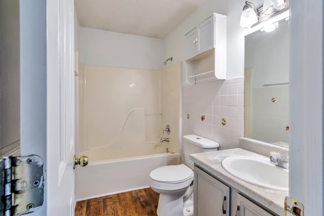 full bathroom with tile walls, tub / shower combination, wood finished floors, toilet, and vanity