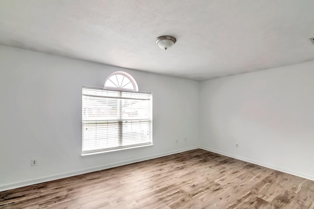 spare room with baseboards and wood finished floors