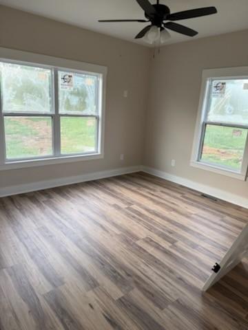spare room with baseboards, ceiling fan, and wood finished floors