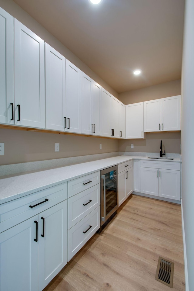 1151 Canaan Rd, Columbia, TN 38401 - kitchen with wine cooler, a sink, light wood finished floors, white cabinets, and recessed lighting