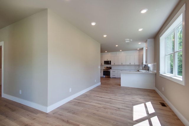 1151 Canaan Rd, Columbia, TN 38401 - kitchen with appliances with stainless steel finishes, white cabinetry, light countertops, decorative backsplash, and light wood finished floors