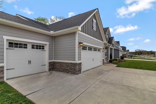 view of property exterior featuring driveway, stone siding, board and batten siding, and a shingled roof
