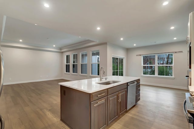 kitchen with a sink, dishwasher, wood finished floors, open floor plan, and recessed lighting