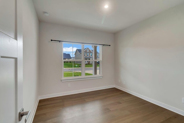empty room featuring wood finished floors, baseboards, and a smoke detector