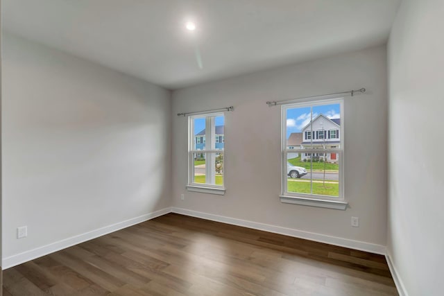 spare room with plenty of natural light, dark wood-type flooring, and baseboards
