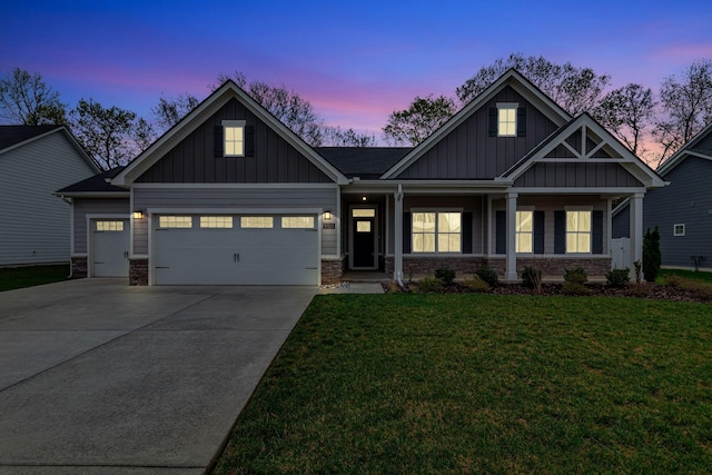 craftsman house featuring board and batten siding, stone siding, an attached garage, a lawn, and driveway