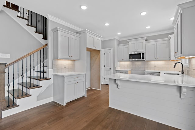 1121 Joe Martin Ln, Lebanon, TN 37087 - kitchen with dark wood-style flooring, ornamental molding, stainless steel microwave, and a peninsula