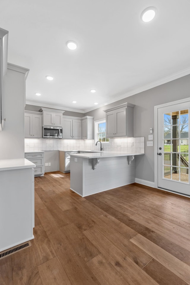 1121 Joe Martin Ln, Lebanon, TN 37087 - kitchen with wood finished floors, a breakfast bar, a peninsula, gray cabinetry, and stainless steel microwave