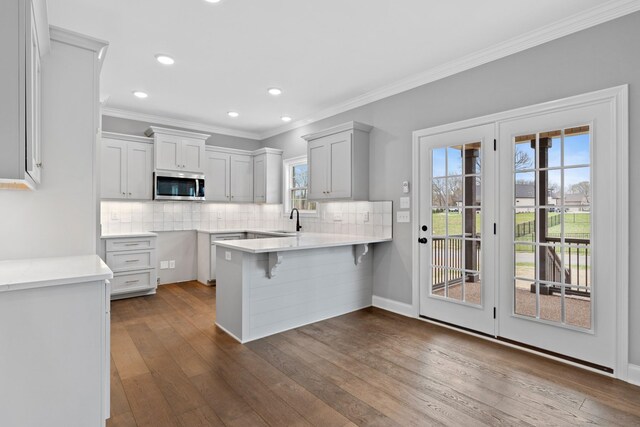1121 Joe Martin Ln, Lebanon, TN 37087 - kitchen featuring dark wood finished floors, a peninsula, backsplash, and stainless steel microwave