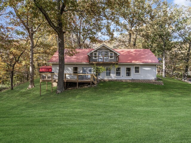 rear view of property with metal roof, a wooden deck, and a yard