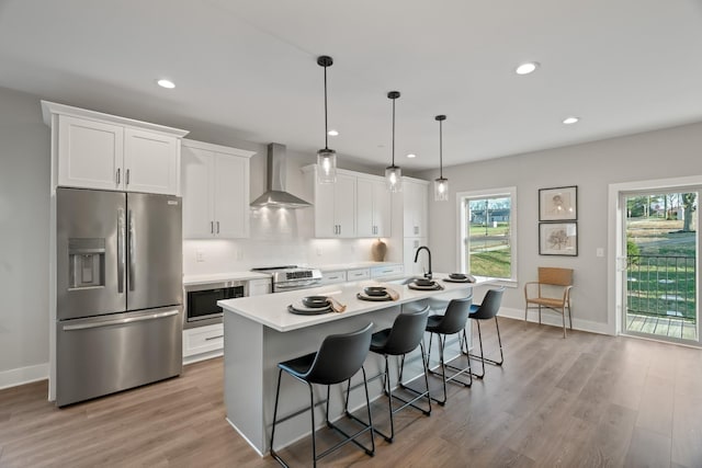 205 Charlotte Everly Cir, Hendersonville, TN 37075 - kitchen with white cabinets, a kitchen island with sink, wall chimney exhaust hood, stainless steel appliances, and a kitchen breakfast bar