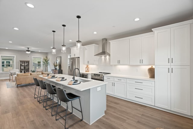 205 Charlotte Everly Cir, Hendersonville, TN 37075 - kitchen featuring a breakfast bar, a kitchen island with sink, appliances with stainless steel finishes, a sink, and wall chimney range hood