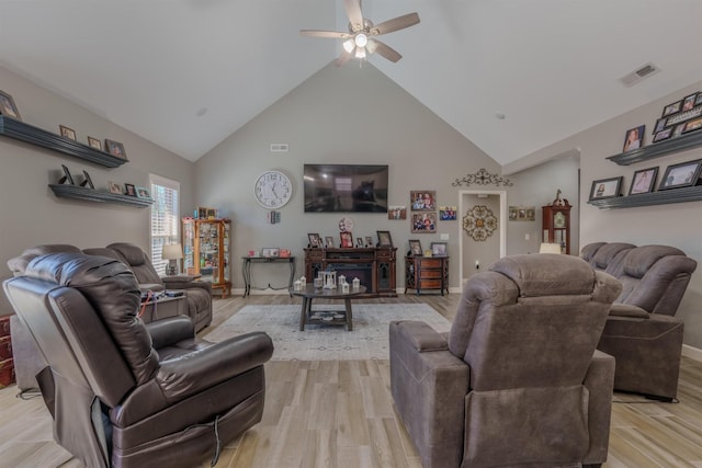 living room with light wood finished floors, visible vents, high vaulted ceiling, and ceiling fan