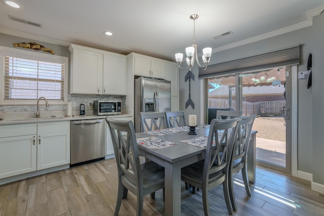 dining room featuring visible vents, crown molding, plenty of natural light, wood tiled floor, and a notable chandelier