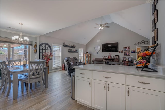 kitchen with light countertops, light wood finished floors, open floor plan, ceiling fan with notable chandelier, and white cabinets