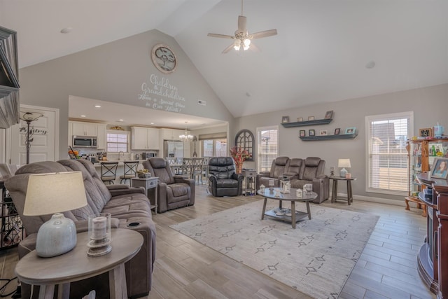 living area featuring recessed lighting, high vaulted ceiling, ceiling fan with notable chandelier, baseboards, and light wood-style flooring