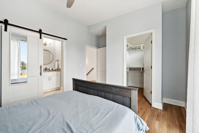 1930D Herman St, Nashville, TN 37208 - bedroom with baseboards, ensuite bath, a barn door, ceiling fan, and light wood-style flooring