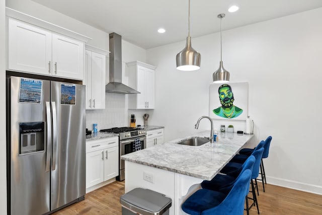 1930D Herman St, Nashville, TN 37208 - kitchen with a kitchen bar, wall chimney exhaust hood, stainless steel appliances, a sink, and light wood-style floors