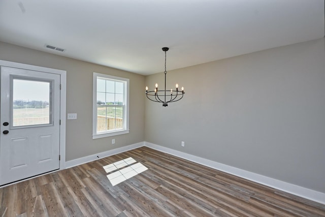 entryway featuring baseboards, visible vents, a chandelier, and wood finished floors
