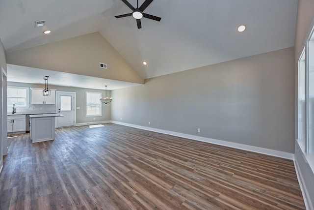 unfurnished living room with a sink, dark wood finished floors, baseboards, ceiling fan with notable chandelier, and visible vents