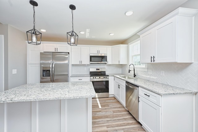 kitchen with a sink, light wood finished floors, white cabinetry, appliances with stainless steel finishes, and decorative backsplash