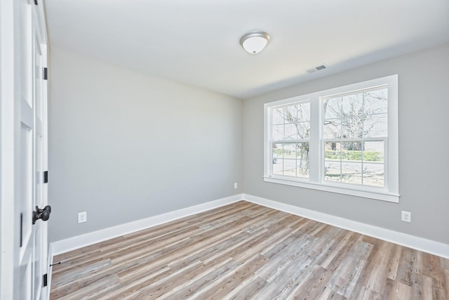unfurnished room featuring baseboards, light wood finished floors, and visible vents