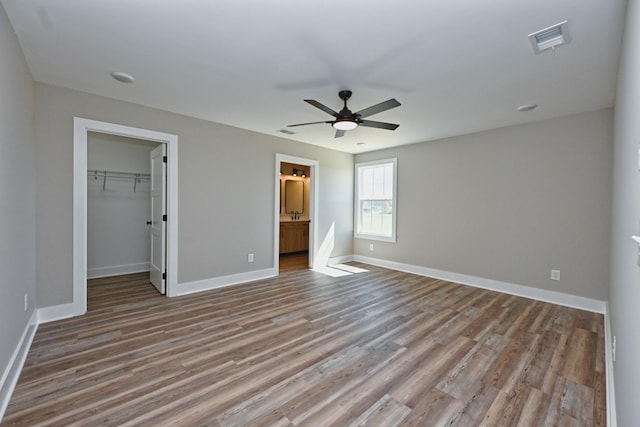 unfurnished bedroom with a closet, a ceiling fan, wood finished floors, baseboards, and visible vents
