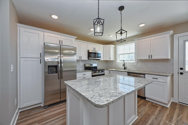kitchen with white cabinets, stainless steel appliances, decorative backsplash, and wood finished floors