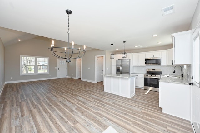 kitchen with a notable chandelier, a sink, a kitchen island, light wood-type flooring, and stainless steel appliances