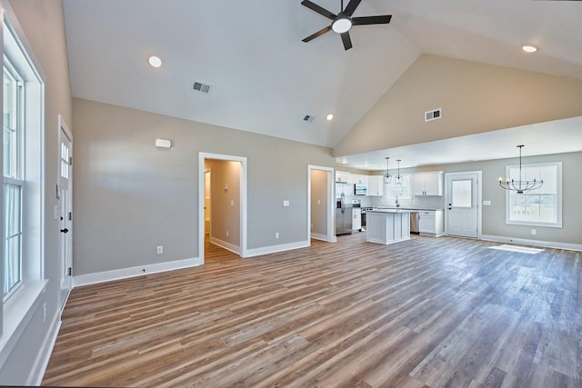 unfurnished living room featuring ceiling fan with notable chandelier, visible vents, and light wood-style flooring