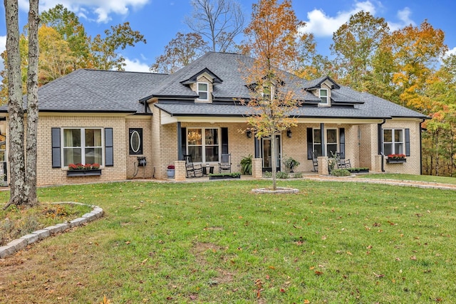 view of front of property featuring brick siding, a front lawn, and roof with shingles