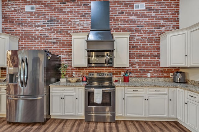 230 Anchor Dr, Waverly, TN 37185 - kitchen with visible vents, stainless steel appliances, brick wall, and wood finished floors