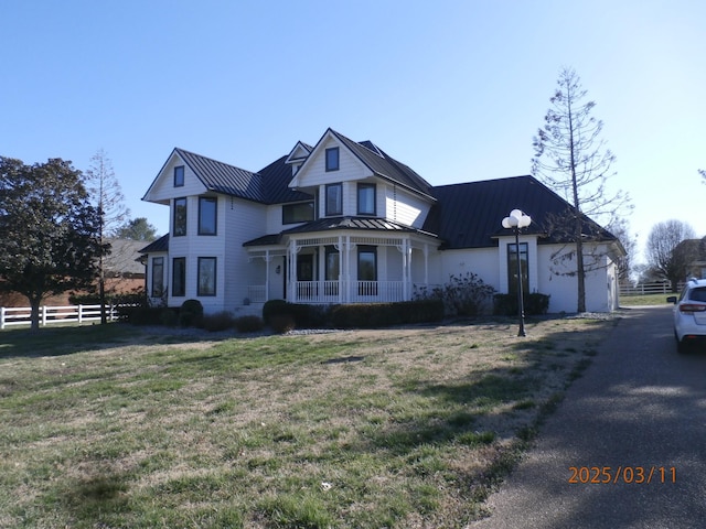 view of front facade with metal roof, fence, a standing seam roof, a front lawn, and a porch