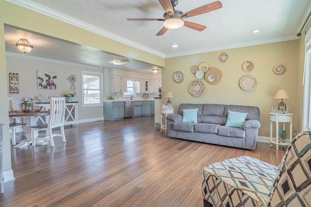 living room with a textured ceiling, dark wood-style floors, baseboards, ceiling fan, and ornamental molding
