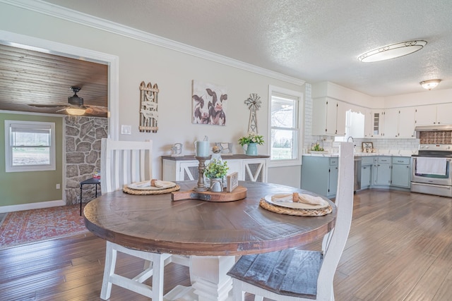 dining room with dark wood-style floors, a textured ceiling, ornamental molding, and a ceiling fan
