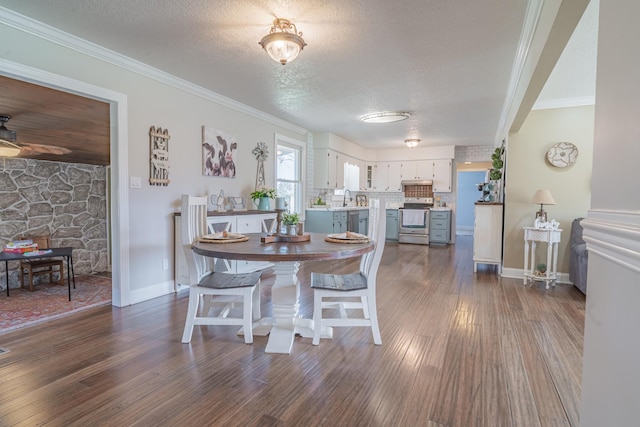 dining area featuring dark wood-style flooring, crown molding, baseboards, and a textured ceiling