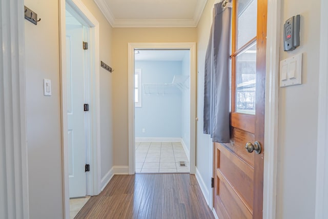 corridor with baseboards, wood finished floors, and ornamental molding