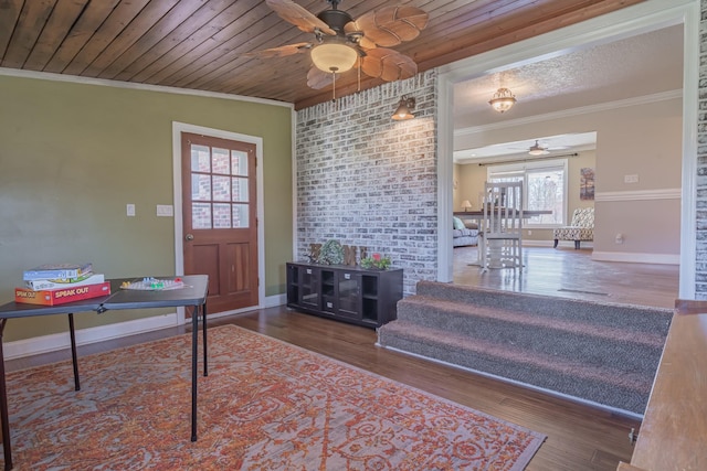 foyer entrance featuring wood ceiling, ceiling fan, wood finished floors, and crown molding