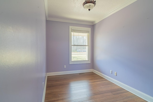 empty room featuring baseboards, a textured ceiling, wood finished floors, and crown molding