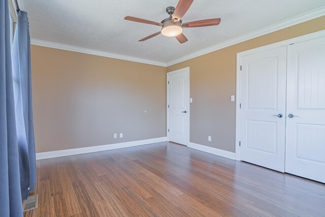 unfurnished bedroom featuring baseboards, visible vents, crown molding, and wood finished floors