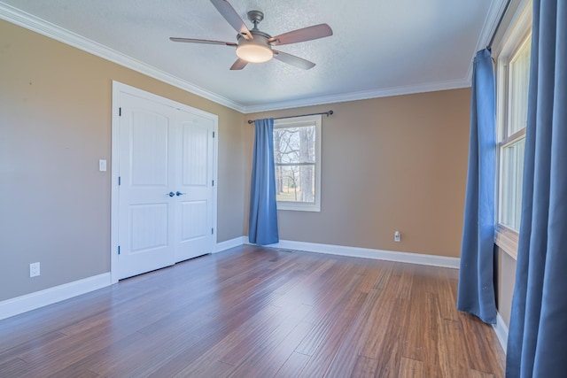 unfurnished bedroom featuring a closet, baseboards, ornamental molding, and wood finished floors
