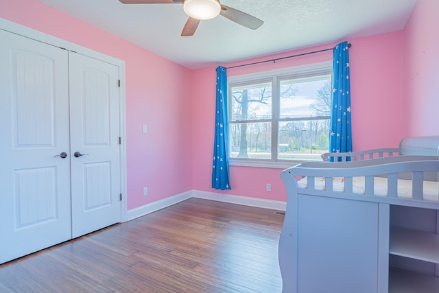 unfurnished bedroom featuring a ceiling fan, a textured ceiling, baseboards, and wood finished floors