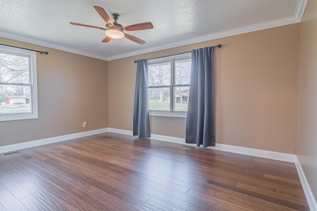 spare room with ornamental molding, visible vents, plenty of natural light, and wood finished floors