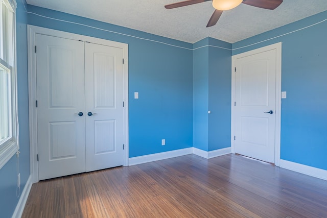 unfurnished bedroom with baseboards, a textured ceiling, ceiling fan, a closet, and wood finished floors