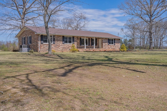 view of front of home with cooling unit, brick siding, and a front yard