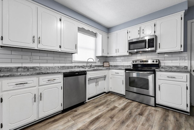 1571 Barrett Dr, Clarksville, TN 37043 - kitchen featuring white cabinetry, backsplash, a sink, appliances with stainless steel finishes, and wood finished floors
